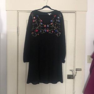 Women’s black dress with embroidered details.